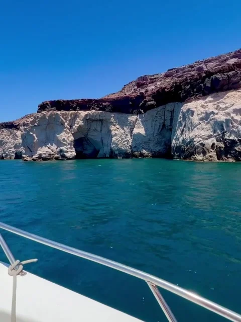 Boat Approaching White and Dark Layered Cliffs with Turquoise Water Video stock 340564316