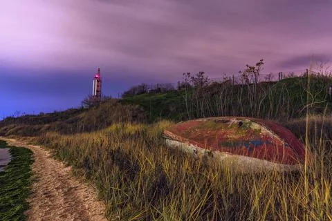 Boat on the beach at night. Lighthouse in the back. Beautiful landscape. Stock Photos