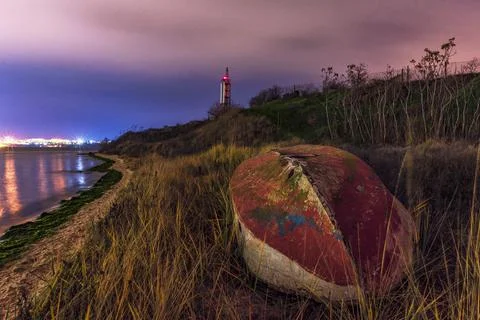 Boat on the beach at night. Lighthouse in the back. Beautiful landscape. Stock Photos