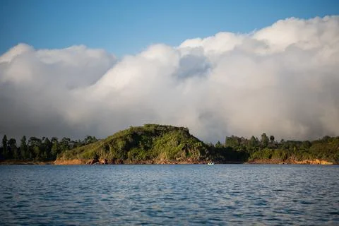 On a boat of a big cloud sitting behind an island. Stock Photos
