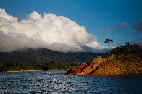 On a boat of a big cloud sitting behind an island. Stock Photos