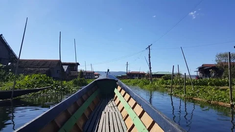 Boat bow sails through canal with houses on stilts, electric poles, Inle Lake Vídeos de archivo 79965137