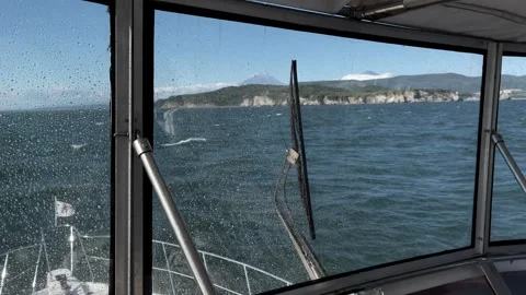 Boat bow view through wet windshield on choppy sea in Kamchatka travel Stock Footage 334107434