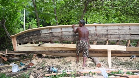 Boat builder repairs wooden hull at Klong Muang Beach Stock Footage 336717094