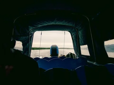 Boat cabin interior viewed from back seat faint figure ahead on calm lake s.. Stock-Fotos