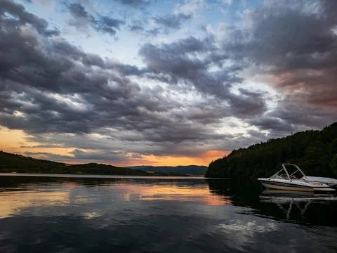 Boat on Calm Lake at Sunset Dramatic Clouds Reflection Landscape Stock Photos
