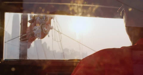 Boat captain steering junk sail boat on a tourist tour with Hong Kong harbor cit Stock Footage 201095963