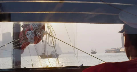 Boat captain steering junk sail boat on a tourist tour with Hong Kong harbor cit Stock Footage 201096986