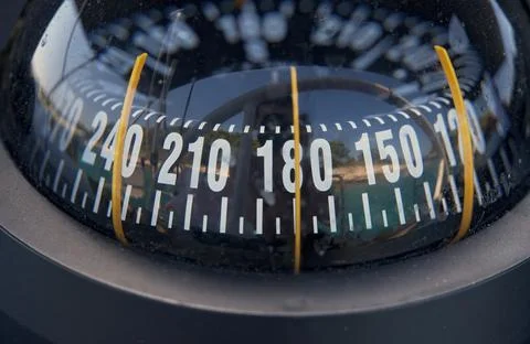 Boat compass showing navigation direction during sailing trip Stock Photos