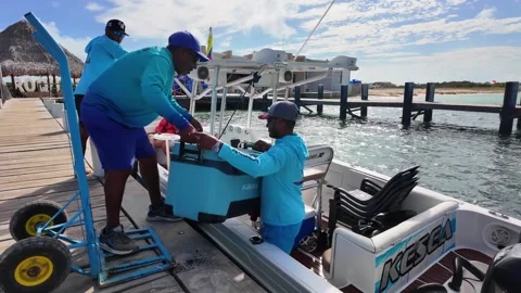 Boat crew loading a large cooler from a wooden pier for a sea excursion Stock Footage 335882946