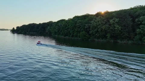 A boat cruises on a tranquil lake, surrounded by forest. Vídeo Stock 312983196