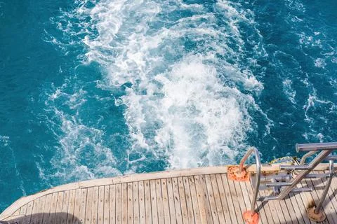 Boat deck overlooking turquoise ocean waters with wake trails for nautical .. Stock Photos