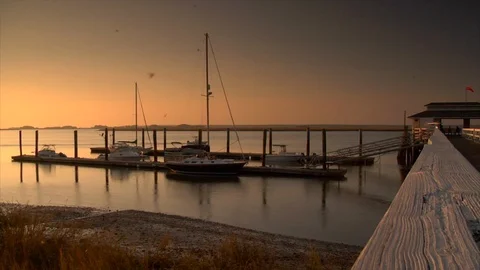 Boat docks and pier at sunset. Moths flying and boat returning Stock Footage 106879876