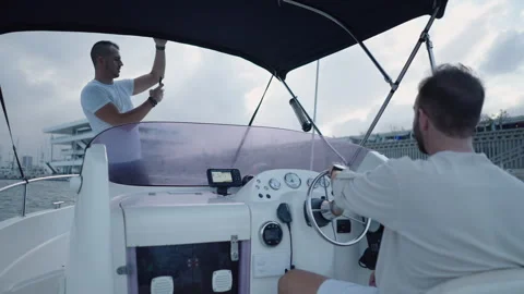 Boat driven by a bearded man next to his friend standing Stock Footage 265908998