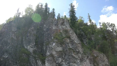 Boat float along river of steep cliffs, sun's rays, cliffs covered with forest Stock Footage 132737199