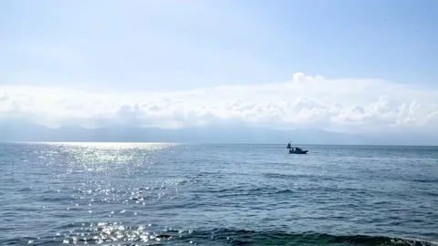 Boat floating alone in the blue ocean with low cloud covered mountain landscape Stock Footage 153464618