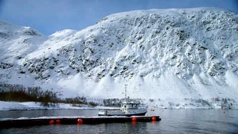 Boat floating on lake water surface with winter mountains and blue sky Stock Footage 121577912