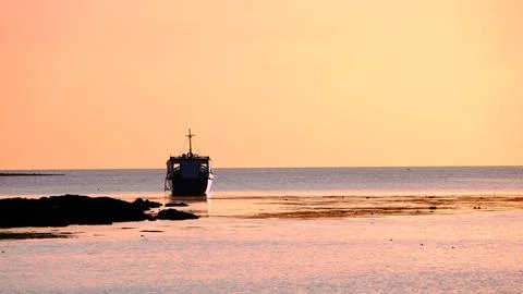 A boat is floating in the ocean at sunset Stock Photos