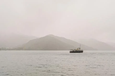 A boat is floating on the ocean under the misty overcast sky Stock Photos