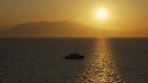 A boat is floating on the sea with the sun setting in the background Stock Footage 320004532