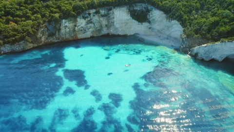 Boat floating in a turquoise bay surrounded by white cliffs and green forest in Stock Footage 308977563