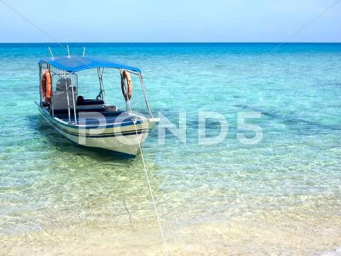 Boat Floating on Turquoise Colored Waters of Tropical Island Stock Photos