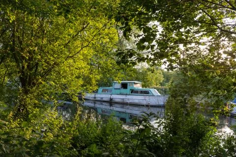 Boat framed by trees at dusk Stock Photos
