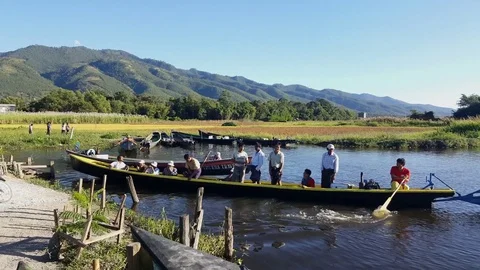 Boat full with passengers leaves dock, green hills in background, Inle Lake Stockbeeldmateriaal 79969603