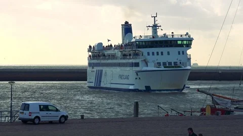 A boat full of passengers turns and sails along the shore, the gray sky in the 库存影片 73965568