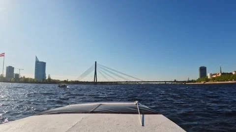 Boat gliding toward the Vanšu Bridge as waves shimmer in the afternoon light Stock Footage 323778264