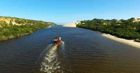 Boat heading down a coastal river towards the ocean Stock Footage 114750545