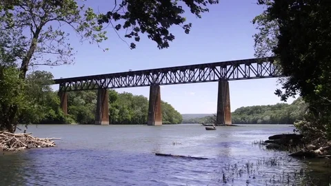 Boat heading up river near train bridge river crossing woods country Stock Footage 71115839