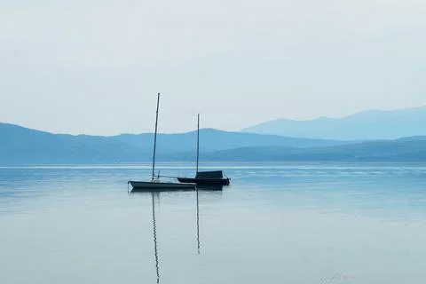 Boat with masts on the water surface against the background of mountains in b Stock Photos