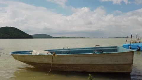 Boat moored moving gently in the wind in lakeside with white clouds Vidéo 132309540