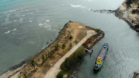 Boat moored on tranquil water surface in a bay with palm trees in the background Stockbeeldmateriaal 143615597