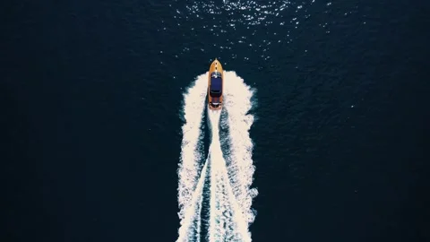 Boat moves through luminous blue ocean creating balanced wake pattern Stock Footage 343175077