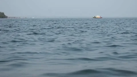 A boat moving in far distance in a clean blue lake with small waves. Stock Footage 131585007