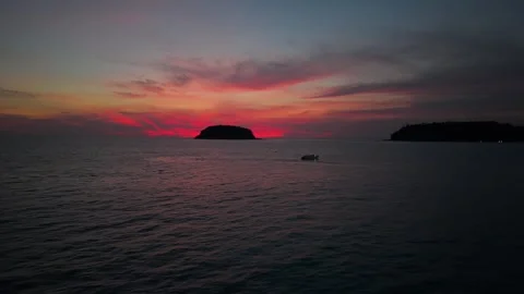 Boat navigates calm waters at sunset near distant island silhouette Видео 342331838