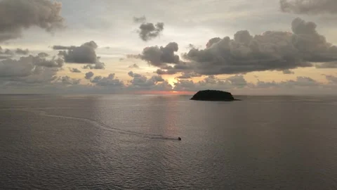 Boat navigates tranquil waters towards island at sunset, clouds above Video stock 342312825