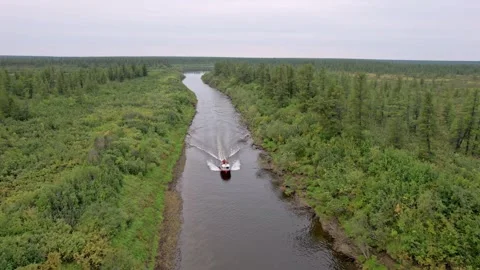 Boat Navigates tundra river. Drone view Of Boat Gliding Along Lush Green Video stock 339634774