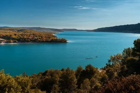 A boat navigates the turquoise blue water of a magnificent lake in Provence Stock Photos