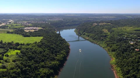 Boat Navigating River Beneath Tancredo Neves Bridge at Border Between Argentina Stock Footage 333728555