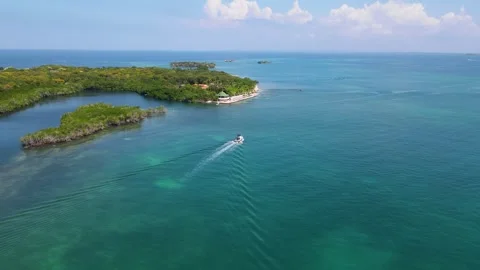 Boat navigating through turquoise waters near lush islands Stock Footage 330449860