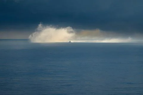 A boat on the ocean emerges from a cloud of mist on the ocean Stock Photos