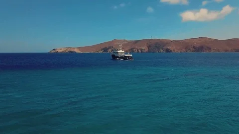 A boat in the ocean in mountains view - pen turn drone shot Stock Footage 98200799