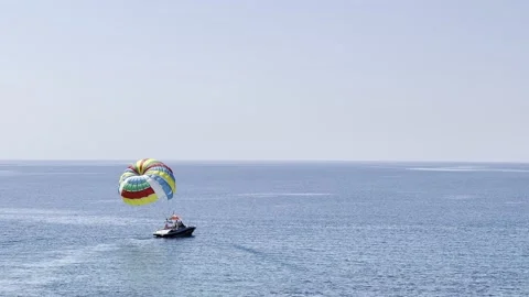 Boat with an open colored parachute floats on the blue sea Stock Footage 200798068