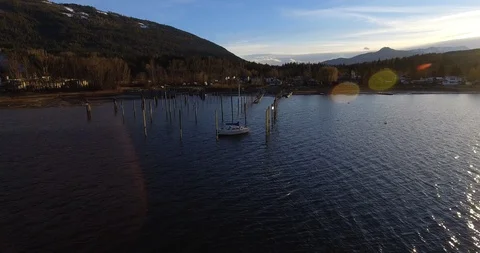 Boat parked at the end of a small dock with beautiful evening sun and mountains Video stock 113321261
