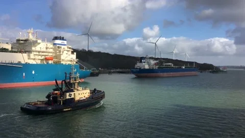 Boat passes large ships with wind turbines in the background at Pembroke, Wales. Stock Footage 172050891