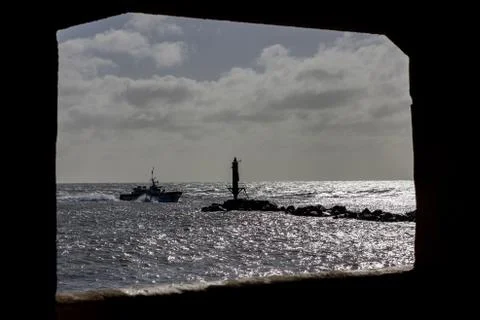 Boat passig the jetty at Ramsgate harbor entrance framed by a window Stock Photos