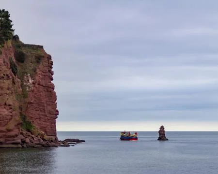 Boat passing a cliff Stock Photos
